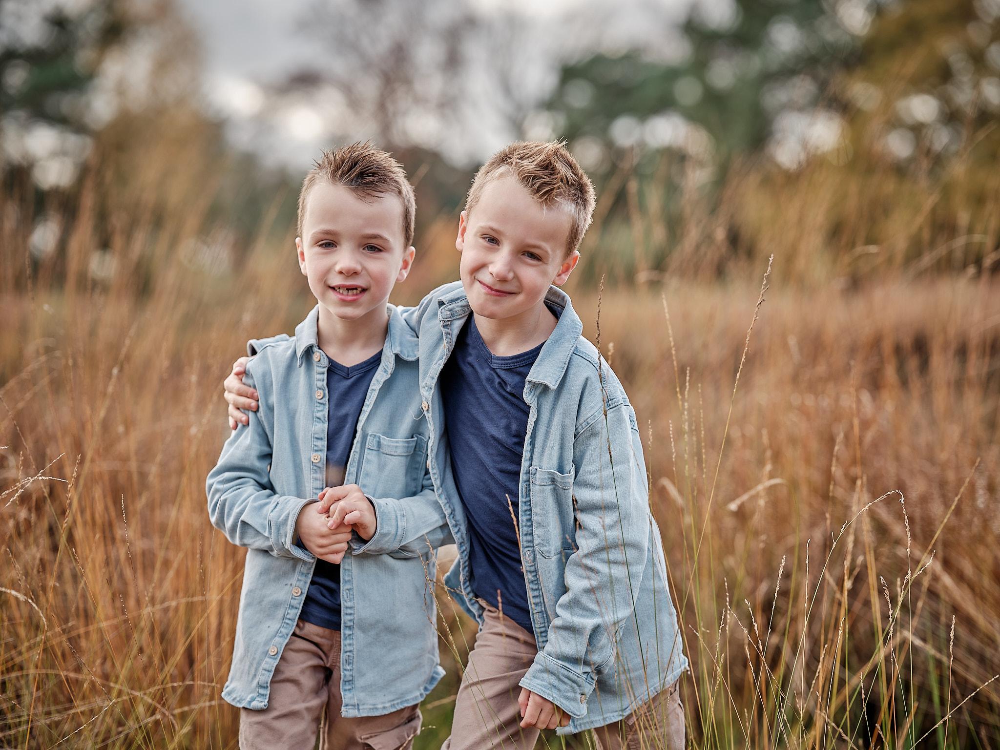 Twee broertjes in het herfstgras – familiefotografie Nijmegen Portret van twee broertjes in het herfstgras tijdens een familieshoot in Nijmegen