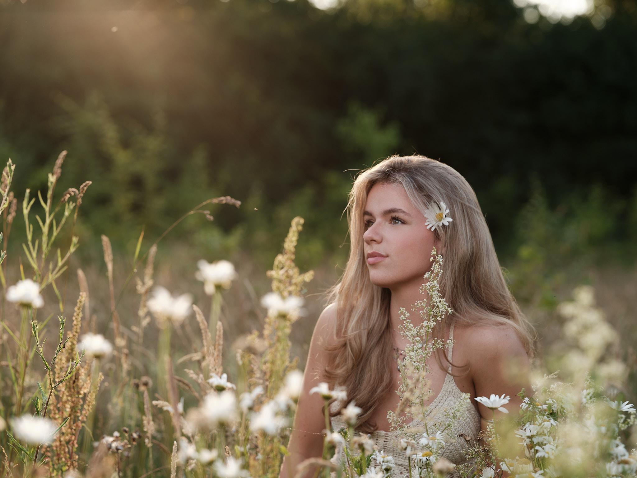 Portret van jonge vrouw in veld met madeliefjes, golden hour buiten Nijmegen.