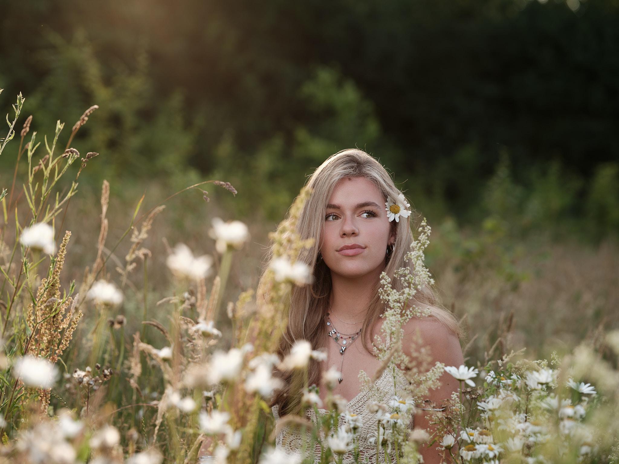 Jonge vrouw in bloemenveld bij zonsondergang, lifestyle portret door portretfotograaf Nijmegen.