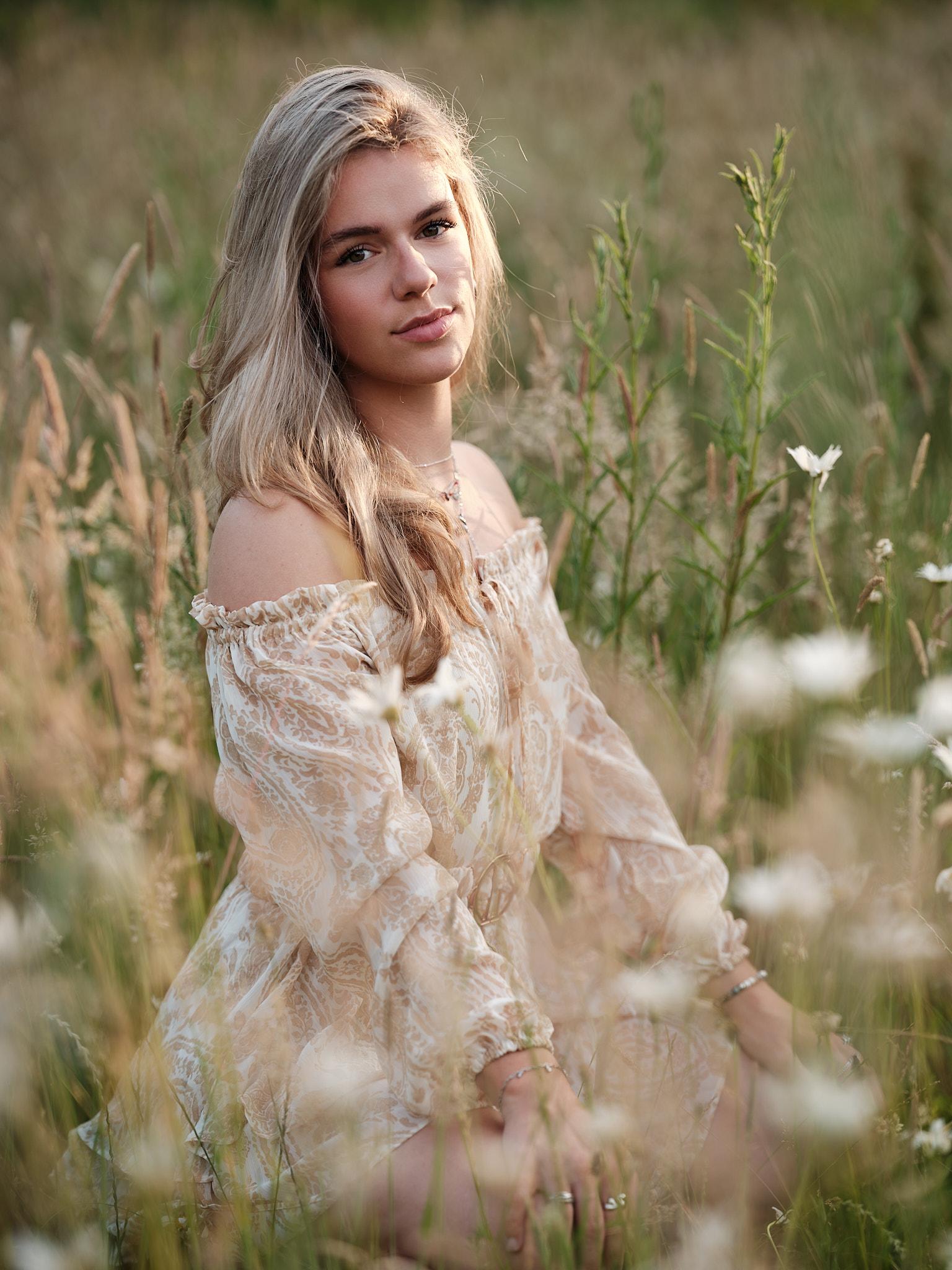 Zachte expressie in zomers veld Model zittend in veld met zachte blik